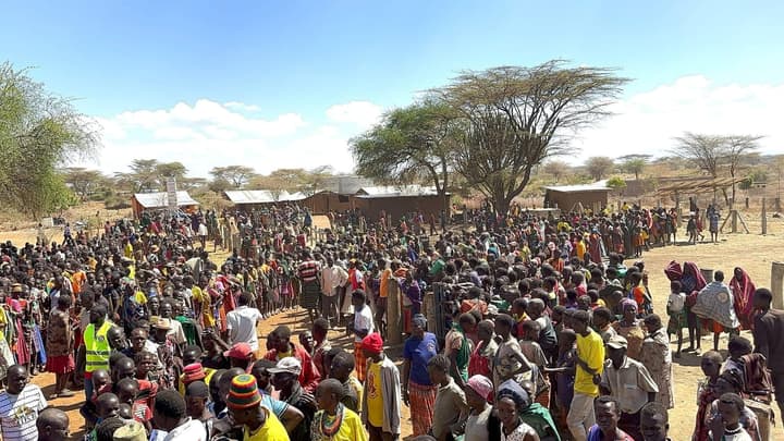 A large crowd at the distribution site, with volunteers in yellow vests